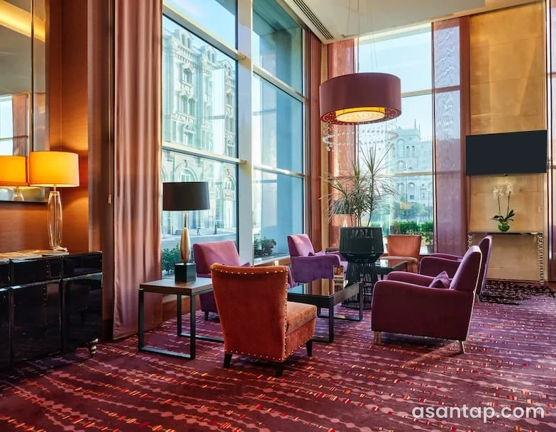 Sugar Lounge — Hilton Baku — iri pəncərələr və yumşaq oturacaqlarla lounge interyeri