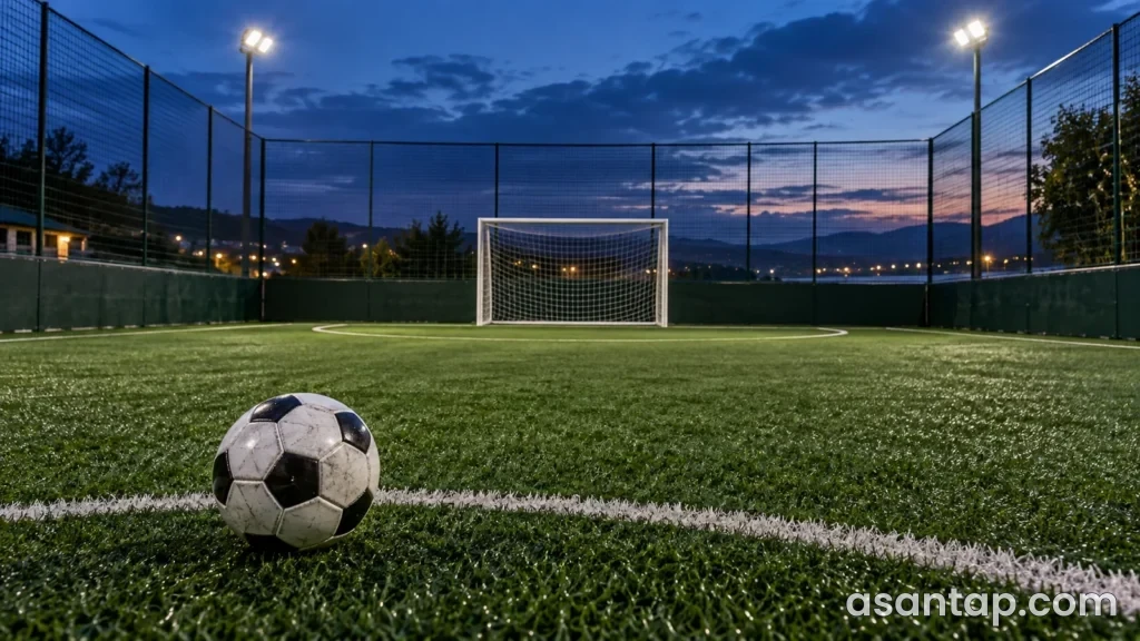 Axşam işıqlandırılmış mini futbol meydançasında top və torlu qapı