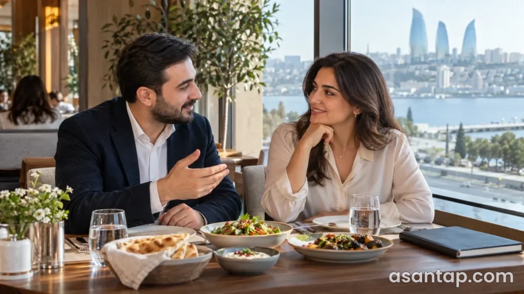 Pəncərə yanındakı restoran masasında nahar zamanı söhbət edən iki iş yoldaşı