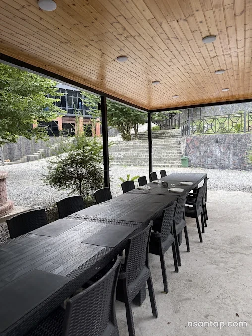 Sım Park restoranının taxta tavanlı örtülü oturma sahəsi və yaşıllığa açılan masaları
