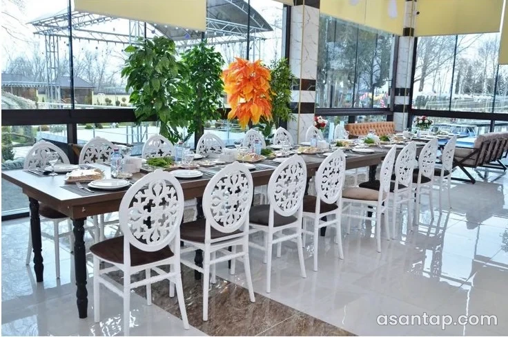 Ağdaş Palace-in bağa baxan şüşəli zalında süfrə və ağ oturacaqlar