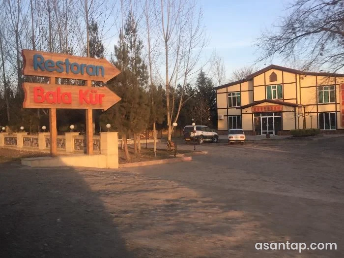 Bala Kür restoranına istiqamət göstərən adlı lövhələr və həyətdəki iki mərtəbəli bina