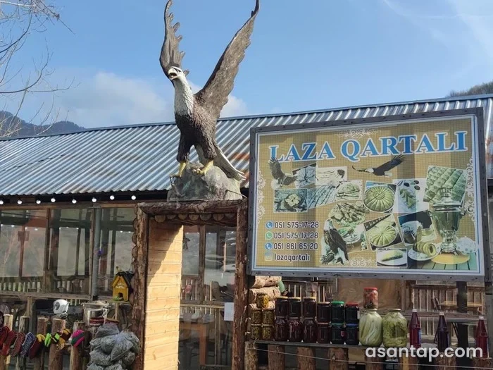 Laza Qartalı restoranının adlı yemək lövhəsi, qartal heykəli və şüşəli taxta tikilisi