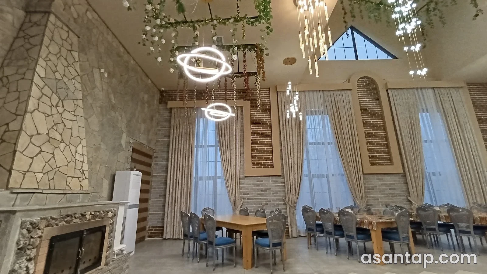 Çuxuryurd restoranının daş divarlı zalı, masalar və işıq kompozisiyası