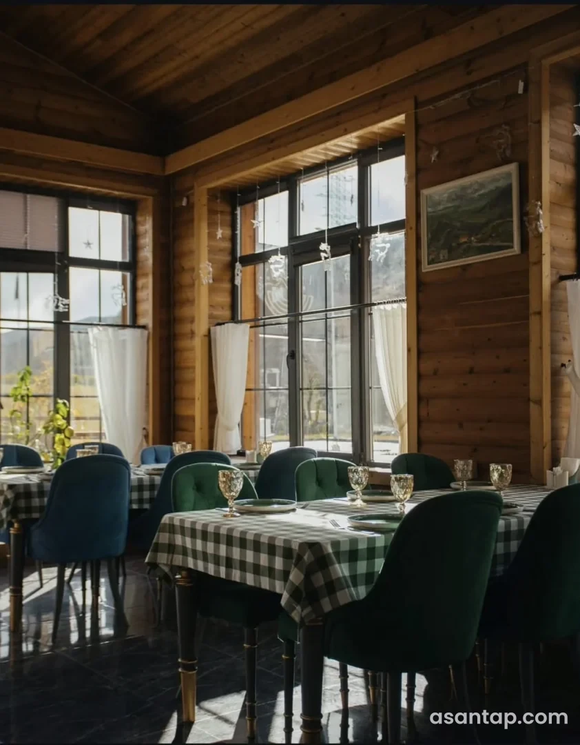 Tree House restoranının taxta divarlı, yaşıl oturacaqlı və damalı süfrəli zalı