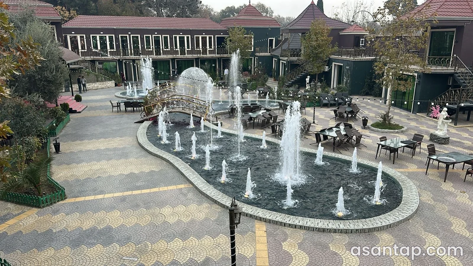 Maqnoliya restoranında fəvvarəli həyət, dekorativ körpü və açıq havada masalar