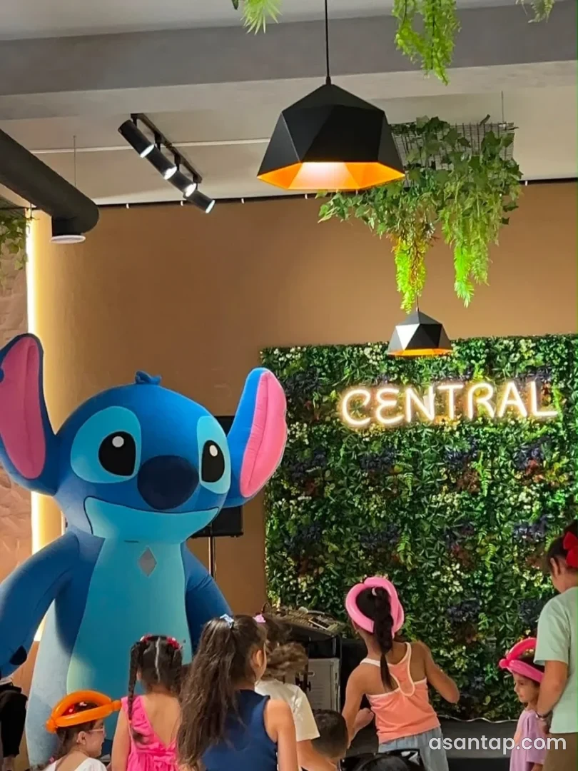 Central Restoranın yaşıl divarlı zalında işıqlı CENTRAL yazısı və uşaq tədbiri