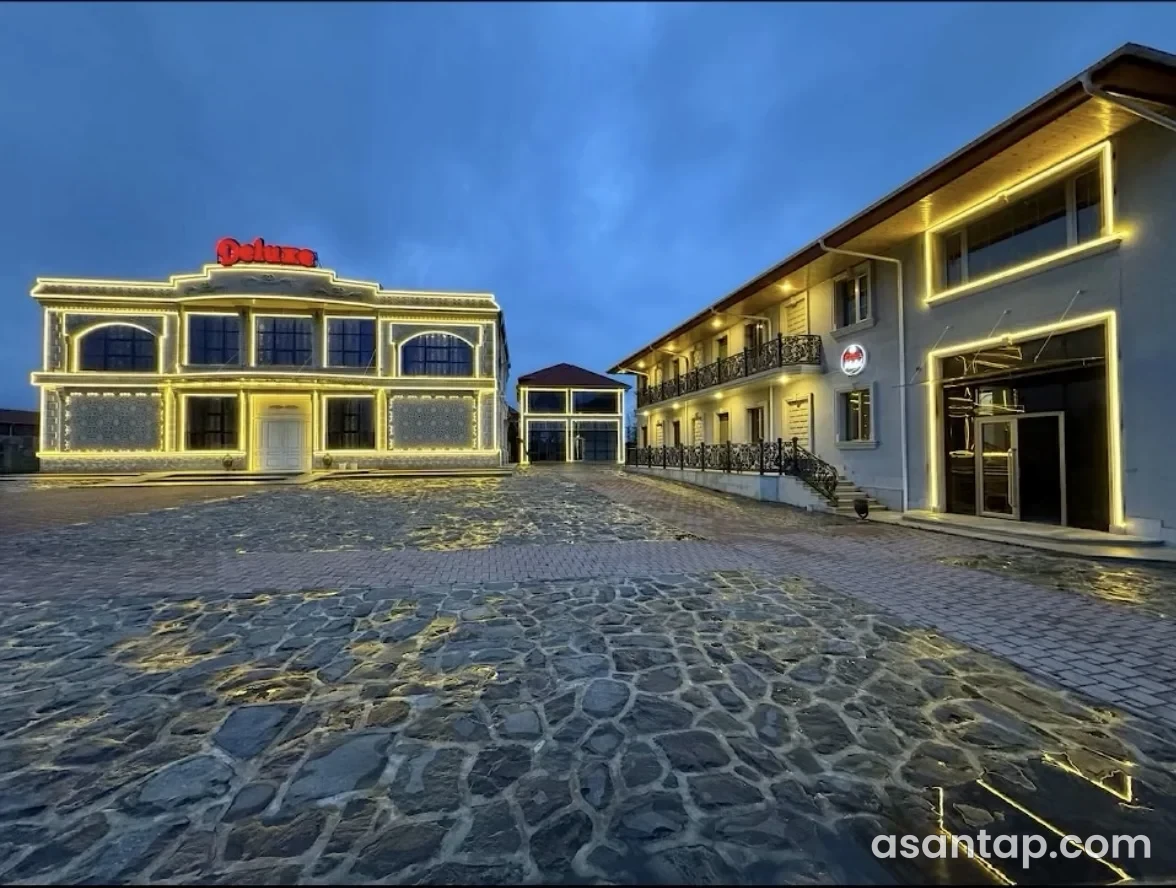 Deluxe kompleksinin işıqlandırılmış əsas fasadı və restoran binası