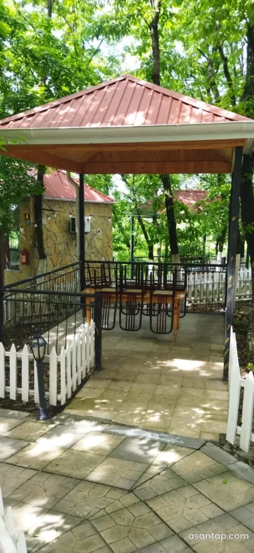 MEH ailəvi restoranının ağaclar arasındakı üstüörtülü besetkası və açıq oturacaq hissəsi