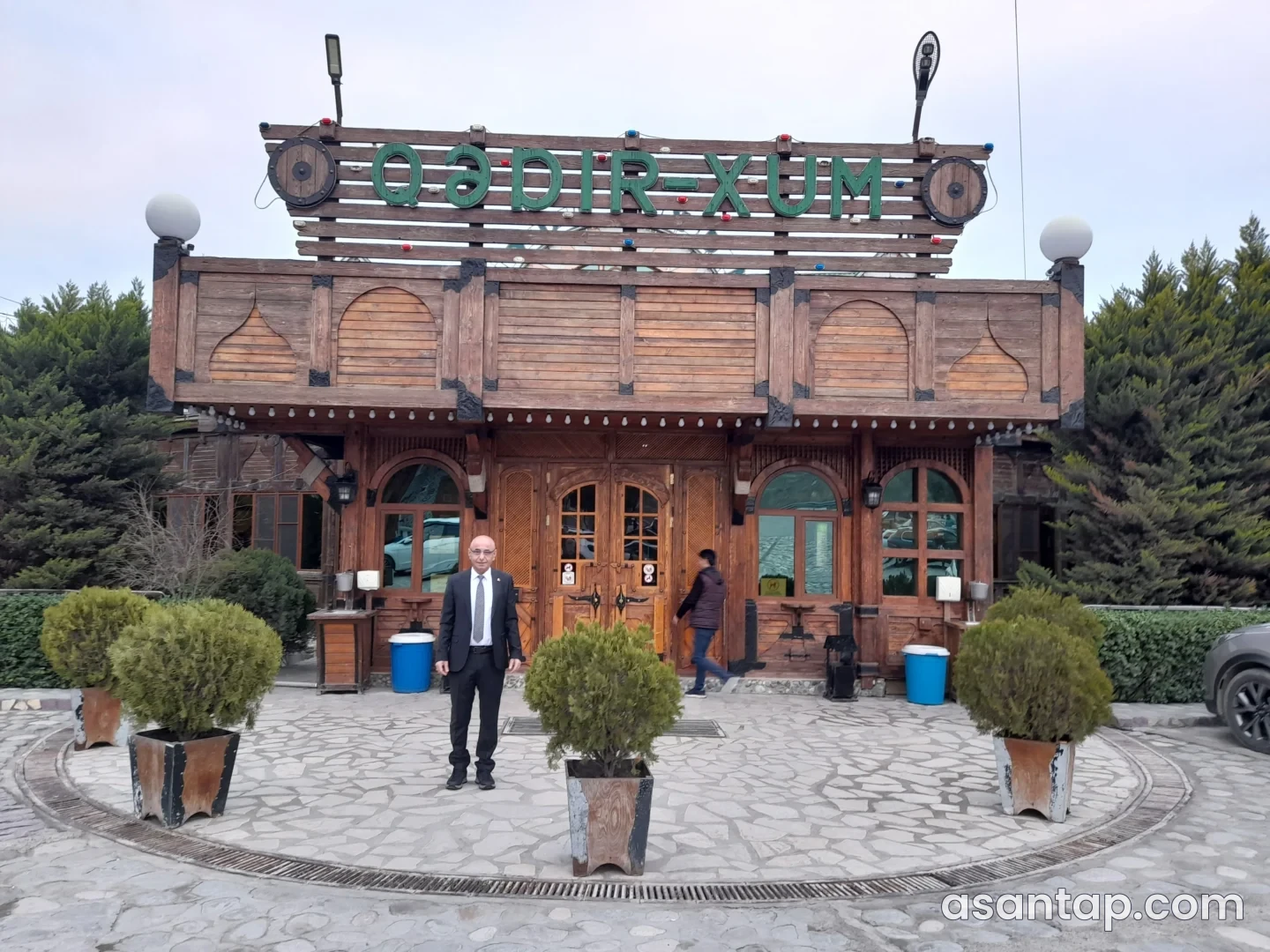 Qədir-Xum restoranının yaşıl adlı lövhəsi və taxta giriş fasadı — mart 2026