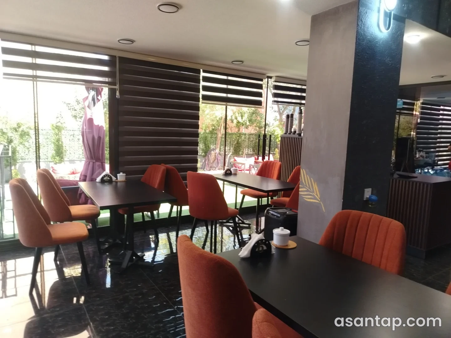 Nira Lounge-un narıncı oturacaqlı zalı, qara masaları və açıq sahəyə baxan iri pəncərələri