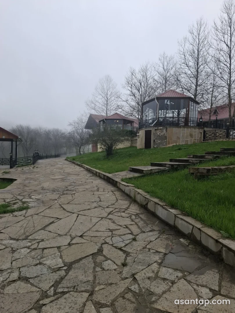 Axırıncı Aşırım Restoranın ağaclar arasındakı şüşəli köşkləri və daş döşənmiş həyəti