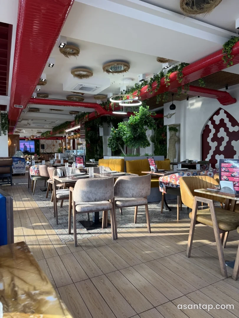 Kəklikotu Restoranın taxta masalı, yumşaq oturacaqlı və qırmızı tavan borulu yemək zalı — noyabr 2025 arxiv fotosu