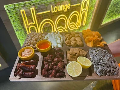 HoQQa Lounge neon lövhəsinin önündə taxta qabda müxtəlif məzələrdən hazırlanmış süfrə