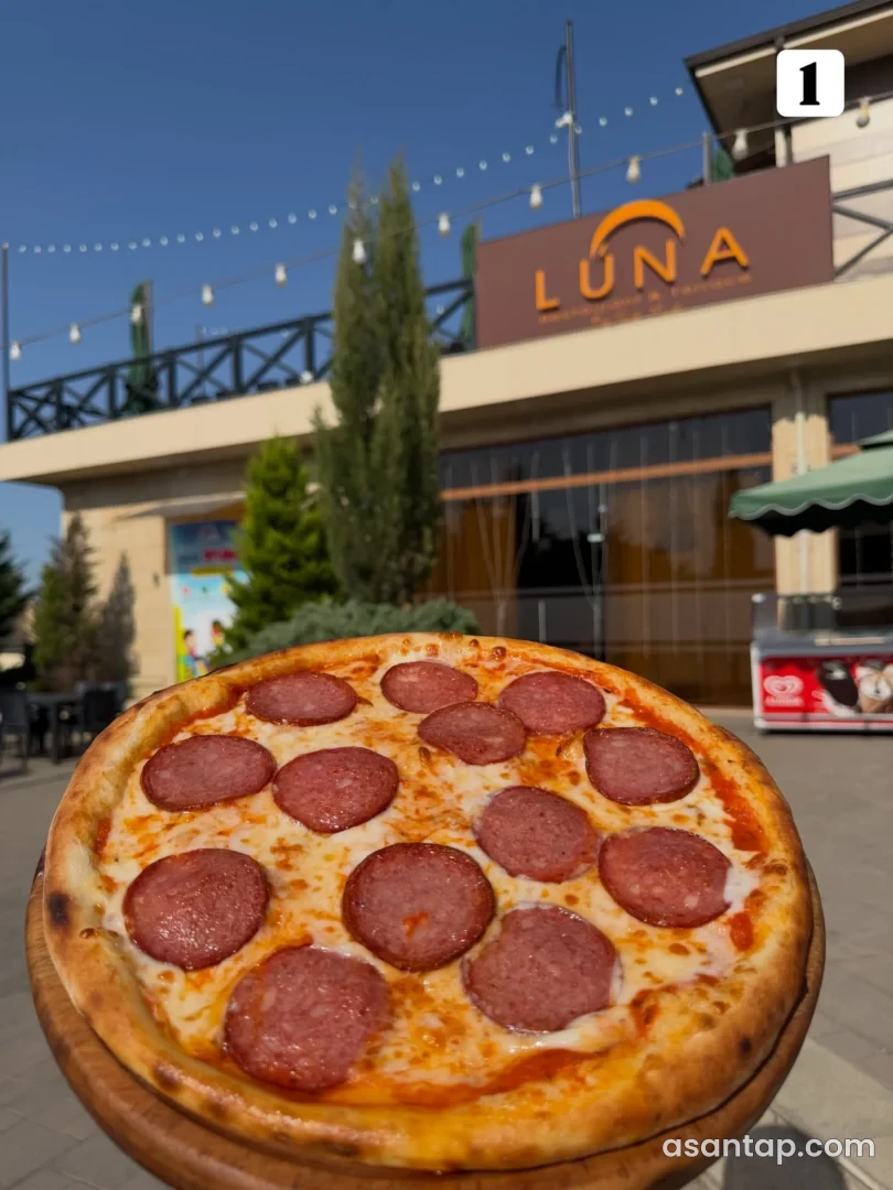 Luna restoranının imzalı fasadı qarşısında pizza təqdimatı