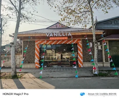 VANILLIA Kofe və şirniyyat evi yazılı daş üzlü fasad, şüşəli giriş və narıncı-ağ şarlar