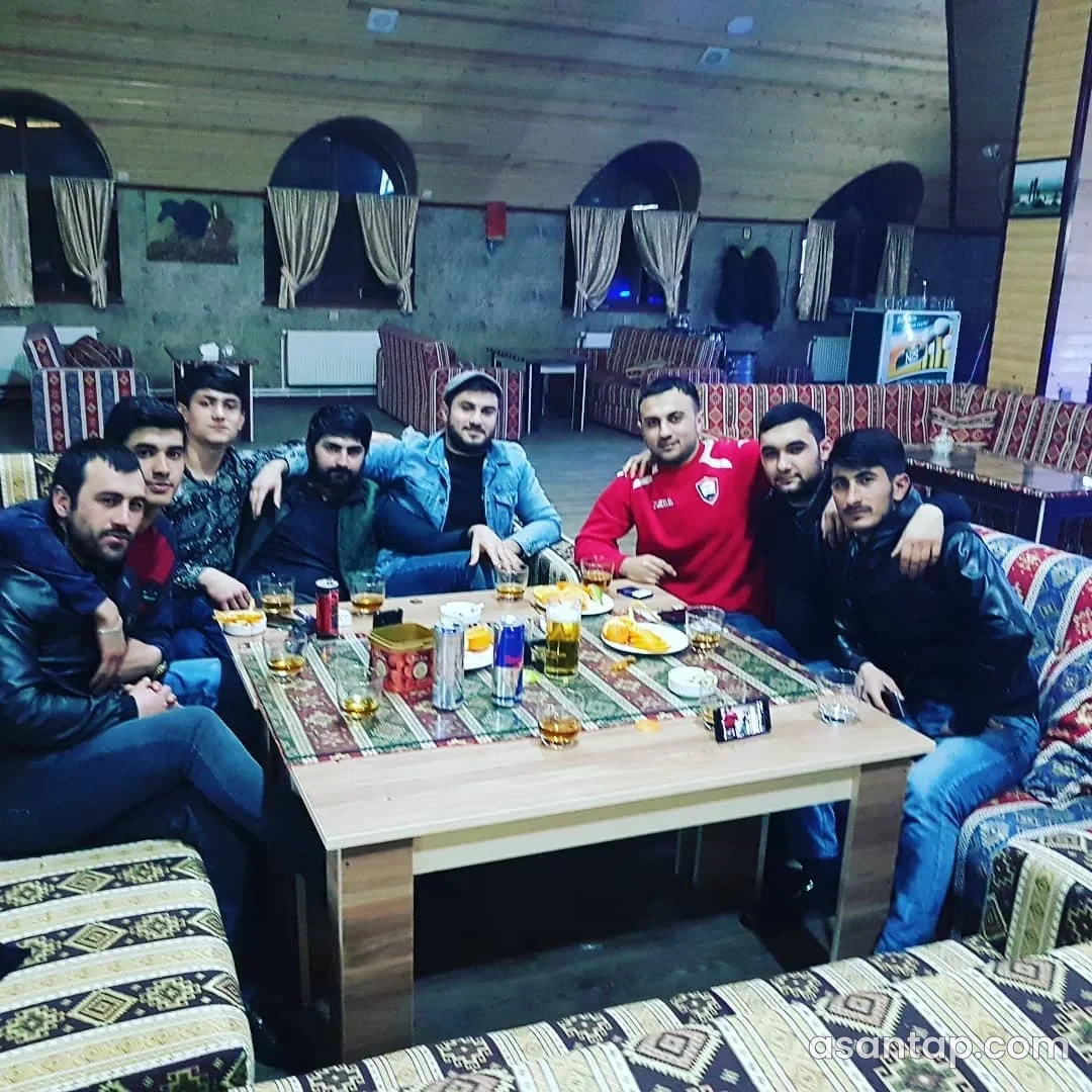 Lion Çay Evinin naxışlı divanlarında çay süfrəsi arxasında qonaqlar, taxta panelli divarlar və tağlı pəncərələr — 2018 arxivi