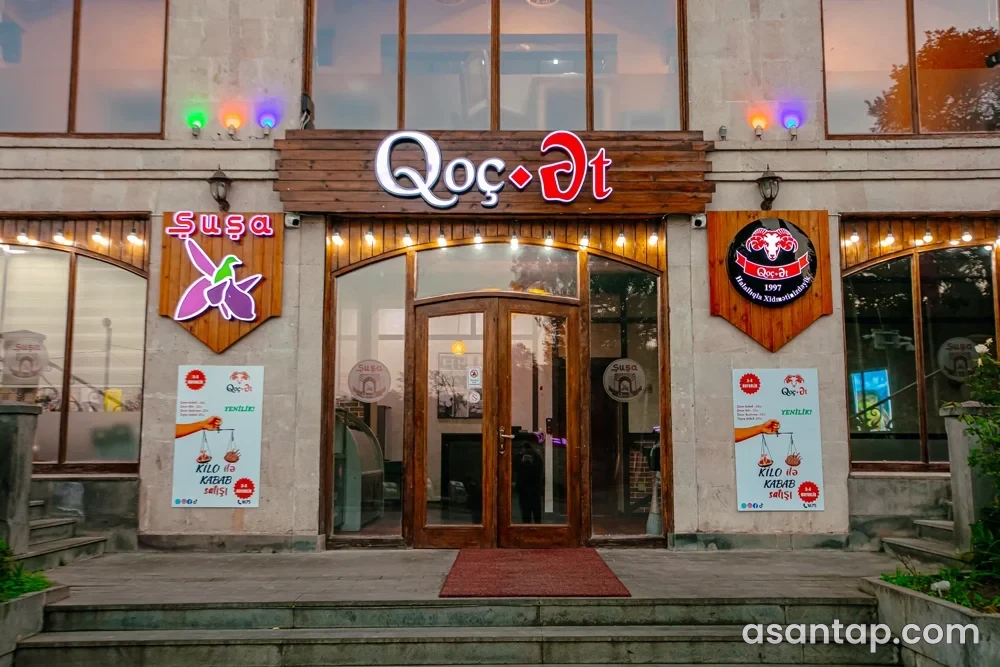 Qoç Ət Şuşa filialının Qoç Ət və Şuşa yazılı daş fasadı və pilləli giriş qapısı