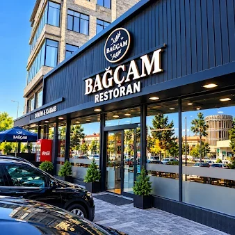 Bağçam Restoran və Dürüm & Kabab yazılı göy fasad, şüşəli giriş və masa sahəsi