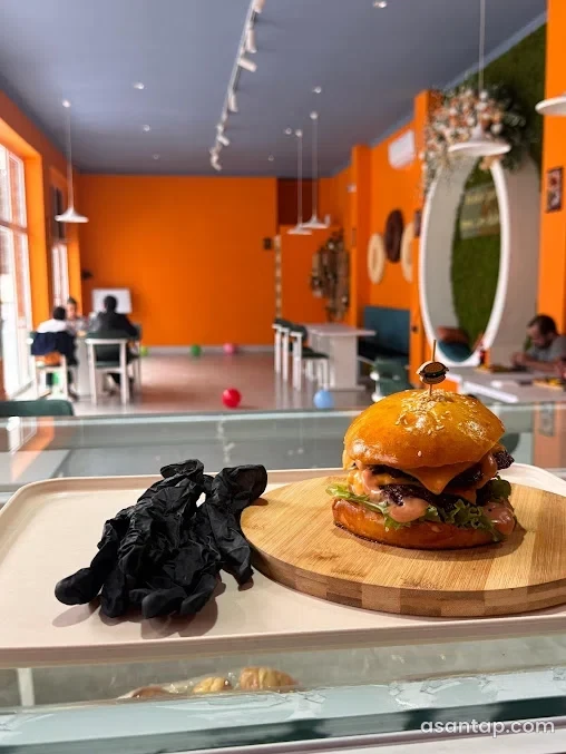 Bublik Cafe-nin narıncı interyeri və taxta lövhədə burger təqdimatı