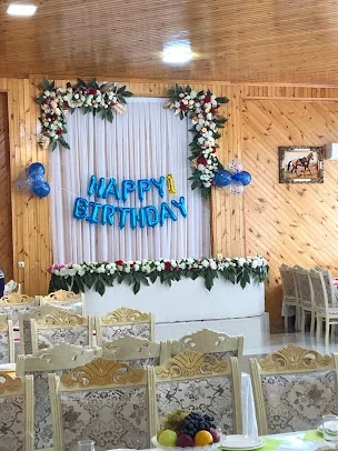 Böyük Dayaq restoranının taxta örtüklü zalı, açıq rəngli stulları və gül çərçivəli dekoru