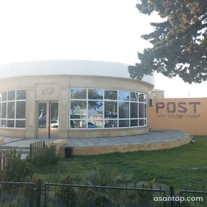Post Cafe-nin yarımdairəvi şüşəli fasadı, POST yazısı və qarşısındakı yaşıl sahə