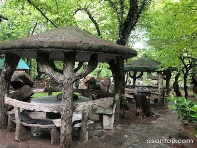 Şəlalə Farel restoranının ağaclı bağında budaq formalı dayaqları və dairəvi oturacaqları olan örtülü pavilyonlar