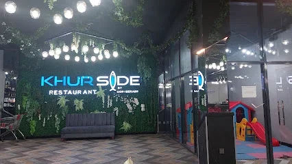 KhurSide restoranının yaşıl dekorlu divarında işıqlı adı və şüşə arakəsməli salonu