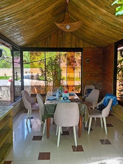 Nur restoranında şüşə divarlı, taxta tavanlı və yemək masalı otaq