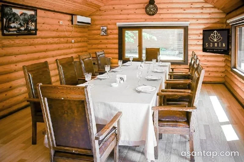 Sərin Ailəvi Restoran nişanlı taxta otaqda ağ süfrəli uzun yemək masası