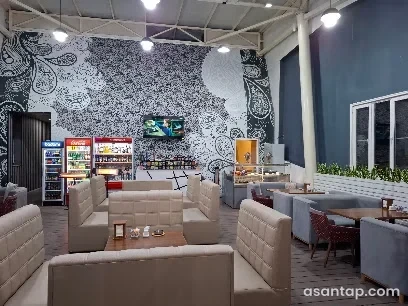Yay Kafesinin açıq rəngli divanlı, naxışlı divarlı və içki soyuduculu zalı