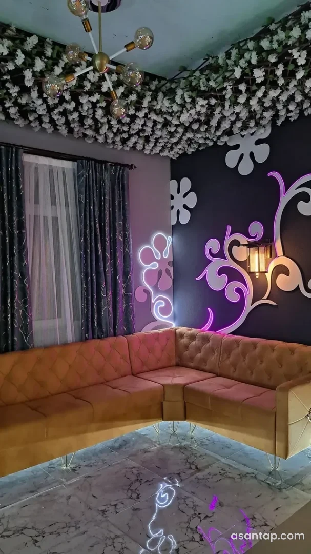 Elegant restoranının ağçiçəkli tavanı, qızılı çilçırağı, neon çiçək naxışlı divarı və künc divanı
