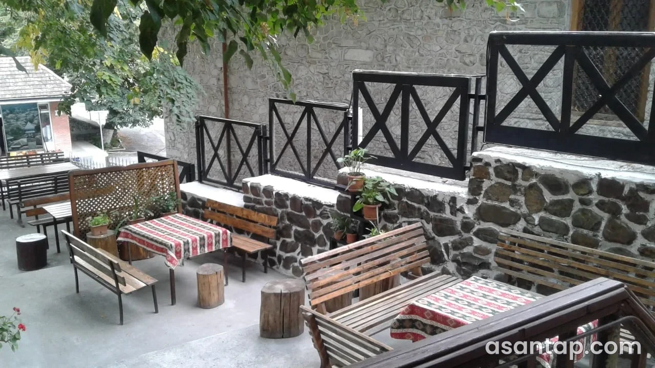 Sultan House restoranının daş divarlı, taxta oturacaqlı və X formalı məhəccərli həyəti