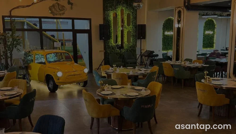 Harika restoranının sarı avtomobil dekorlu, yaşıl və sarı nişanlı stulları olan salonu