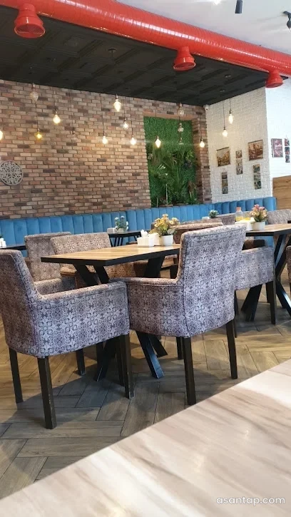 İzmir restoranının kərpic divarlı, mavi divanlı və qırmızı tavan borulu zalı