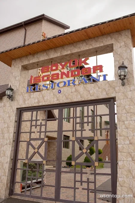 Böyük İsgəndər restoranının yazılı daş giriş portalı və naxışlı metal qapısı