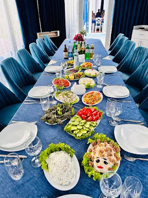 Aquamarine Fish House-un mavi stullu yemək otağında uzun masa və hazırlanmış süfrə