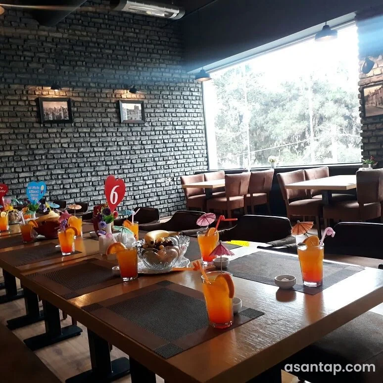 Əriştə restoranının boz kərpicli, iri pəncərəli və qəhvəyi oturacaqlı salonu