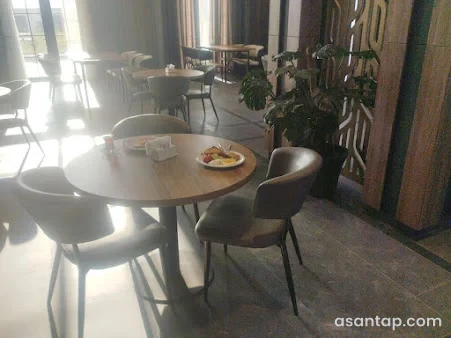 Ağalı Hotel restoranının dairəvi masalı və yumşaq stullu yemək salonu