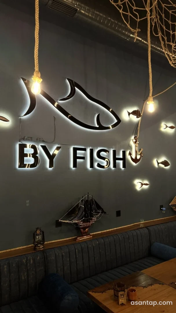 BY FISH restoranında işıqlı balıq fiqurları, gəmi maketi və kəndir lampaları olan oturma guşəsi