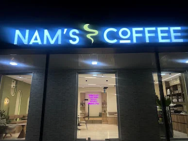 NAM’S COFFEE-nin işıqlı ad lövhəsi, şüşəli girişi və görünən bar guşəsi