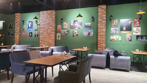 Beerqosa pubının yaşıl divarlı, kərpic sütunlu və boz kreslolu zalı