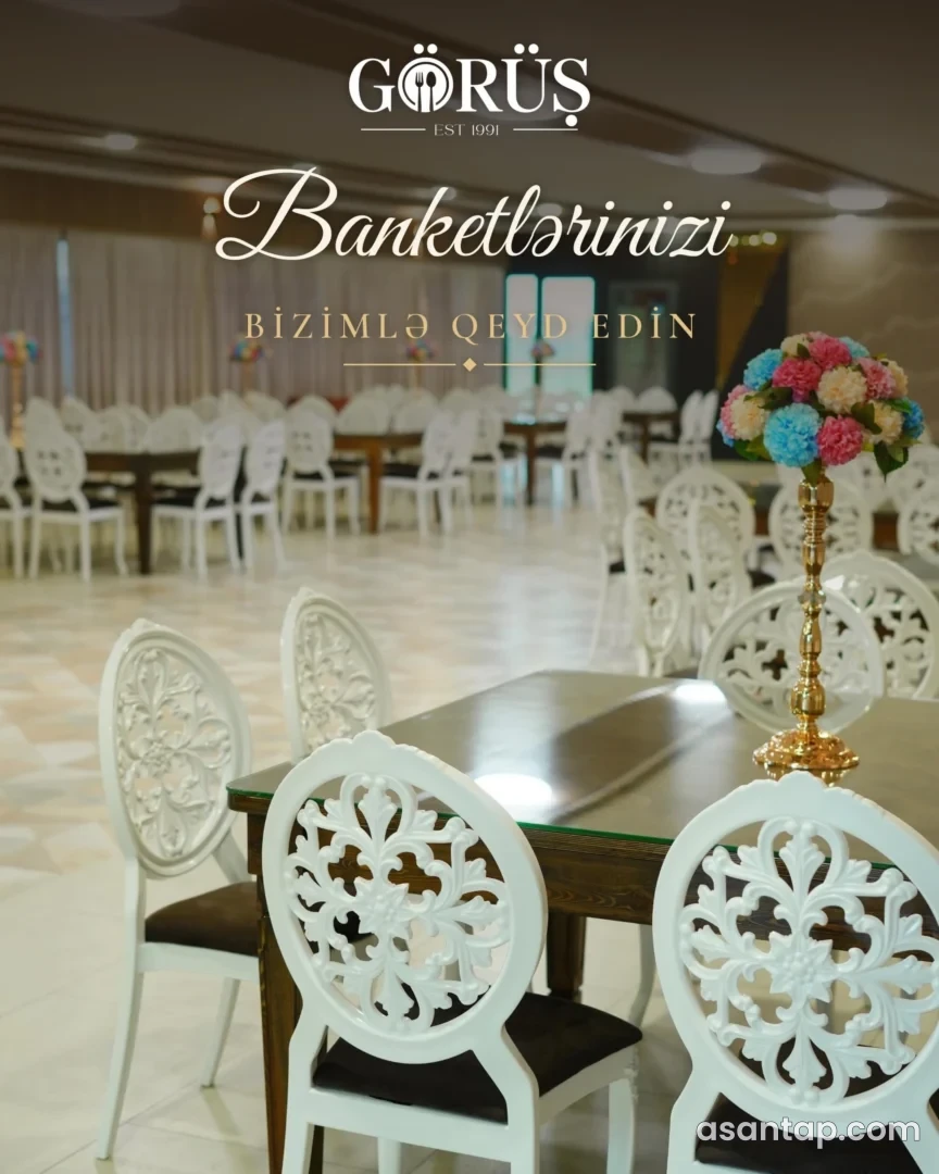 Görüş restoranının masa, ağ naxışlı stullar və gül kompozisiyaları ilə banket zalı; operatorun foto üzərindəki təqdimat yazısı