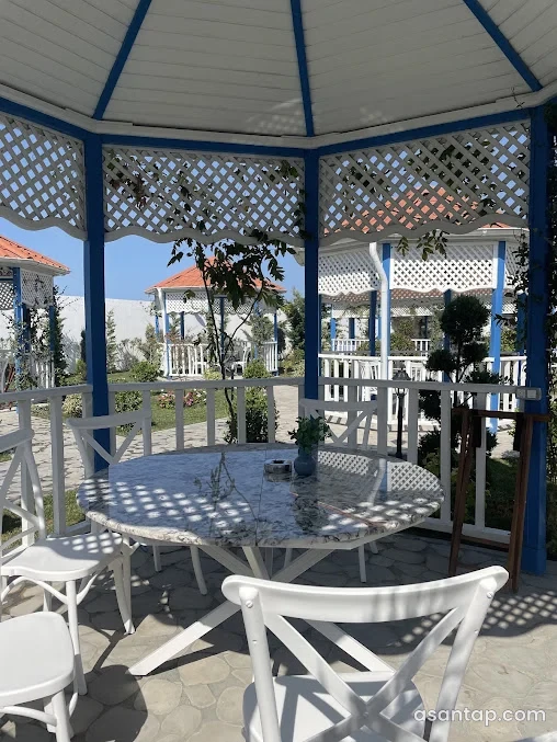 Yelkən restoranında ağ və göy rəngli açıq söhbətgahlar və masa