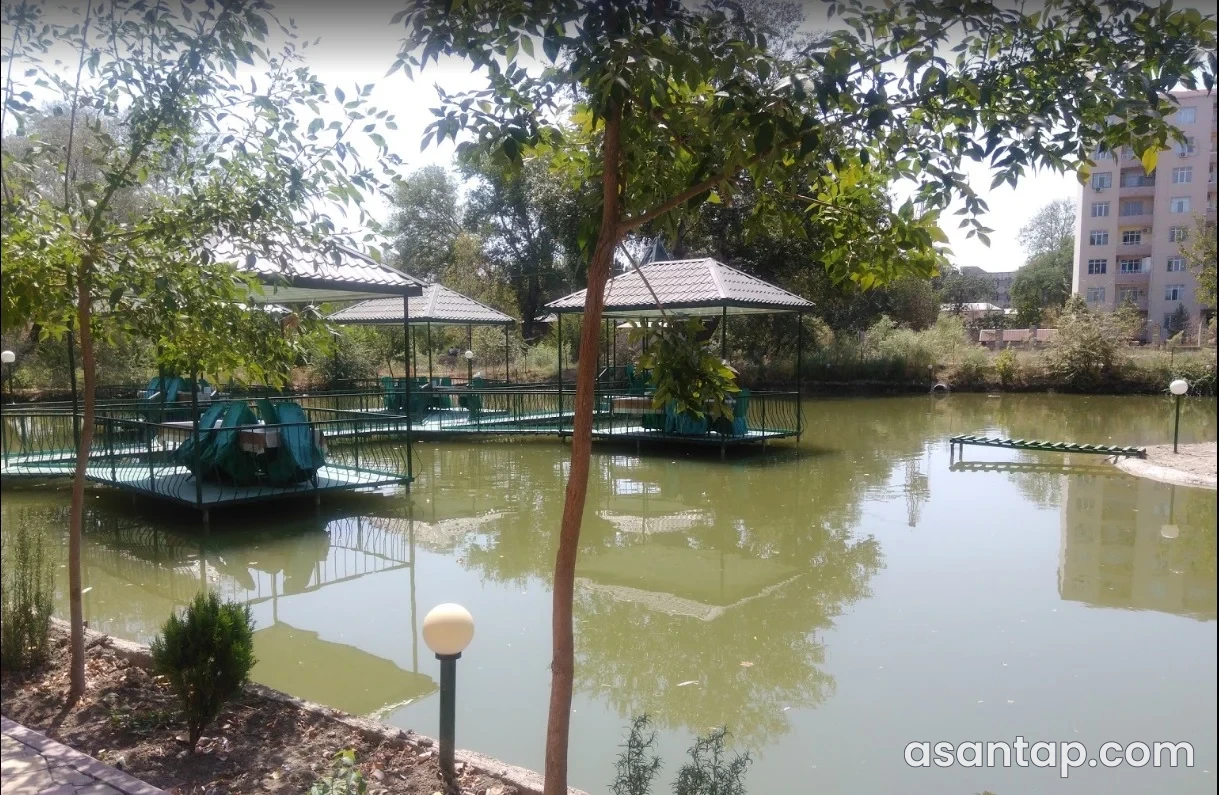 Prins restoranının su hövzəsi üzərindəki örtülü yemək köşkləri və ağaclı həyəti