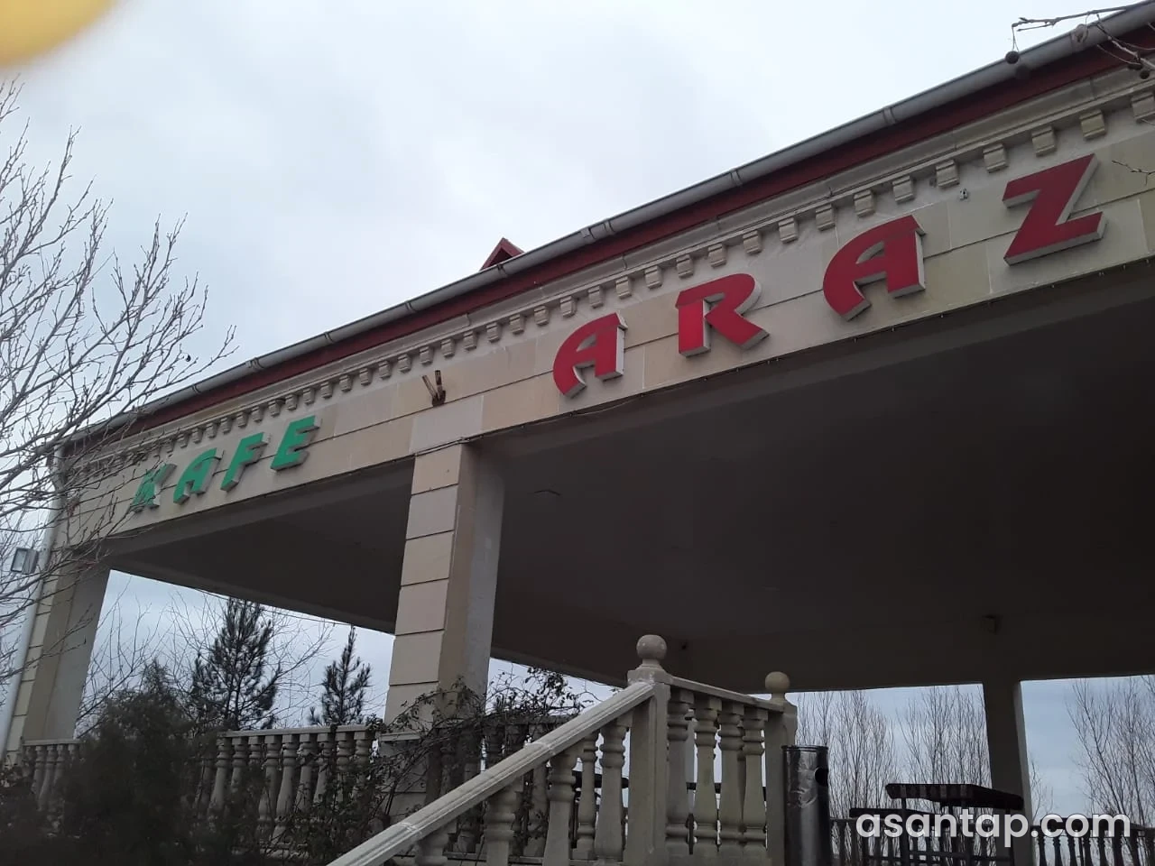 Araz kafesinin qırmızı ARAZ yazılı açıq eyvanı və daş məhəccərli pilləkəni