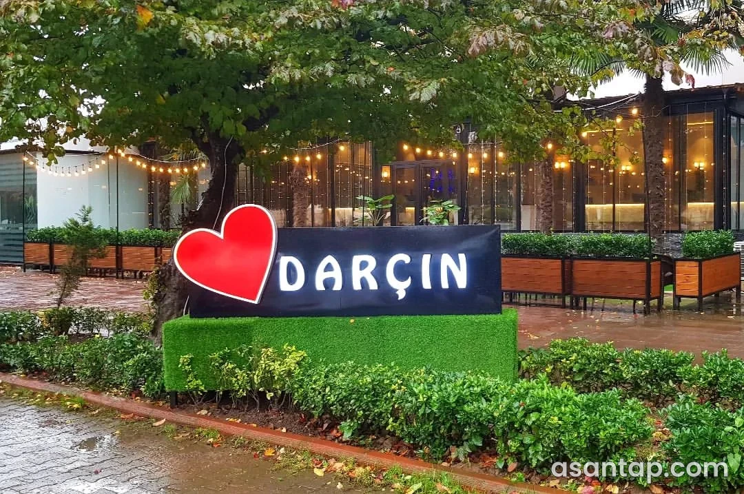 Darçın House restoranının ağaclar arasındakı şüşəli fasadı və qırmızı ürəkli işıqlı Darçın lövhəsi