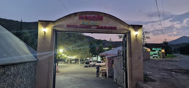 Məngük ailəvi istirahət mərkəzinin yazılı tağlı girişi və ağaclı həyəti