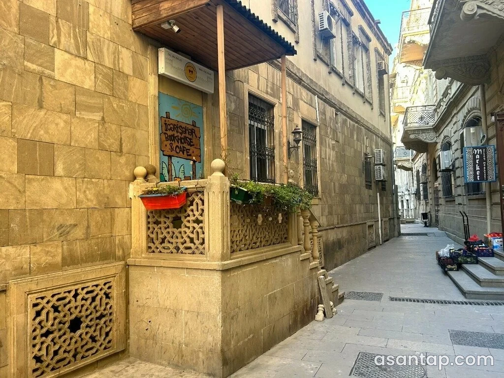 İçərişəhər Bookhouse & Cafe-nin daş fasadı və ağaclarla bəzədilmiş giriş hissəsi