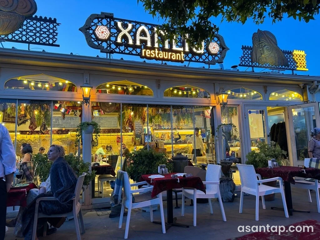 Xanlıq Restaurant-ın açıq oturma sahəsi və işıqlı restoran lövhəsi